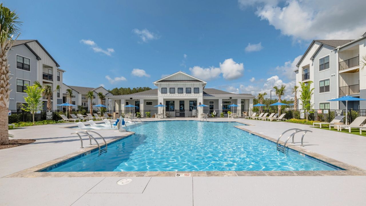 Beautiful clubhouse exterior with seating area and a pool
